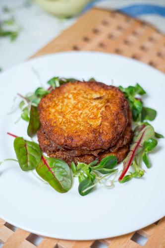 a white plate with a piece of meat on a salad at Nykščio Namai & SPA in Anykščiai