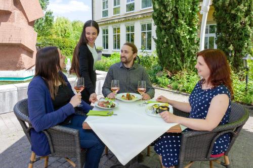 a group of people sitting around a table with wine glasses at Best Western Wein- und Parkhotel in Nierstein