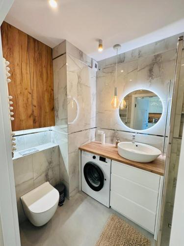 a bathroom with a sink and a washing machine at Apartament Nadmorski in Gdańsk
