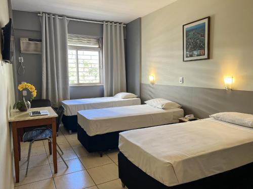 a hotel room with three beds and a table at Riviera Hotel in Brasilia