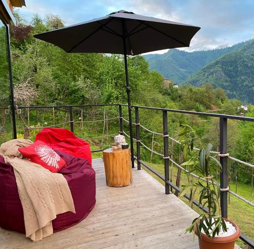 an umbrella sitting on a wooden deck with a table at House in mountains, near Batumi- Lemanor Lodge in Kʼveda Chʼkhutunetʼi
