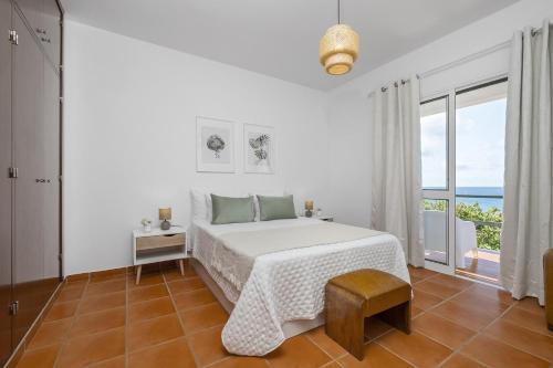a white bedroom with a bed and a large window at Villa Bella Mar by Madeira Sun Travel in Porto Santo