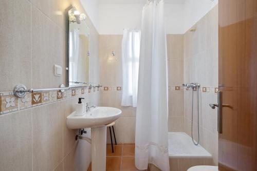 a white bathroom with a sink and a shower at Villa Bella Mar by Madeira Sun Travel in Porto Santo