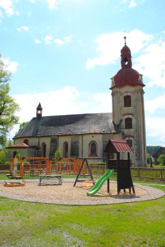 a playground in front of a building with a church at Penzion na Faře in Dubenec