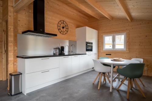 a kitchen with white cabinets and a table with chairs at Recreatiepark Maas en Bos in Wellerlooi