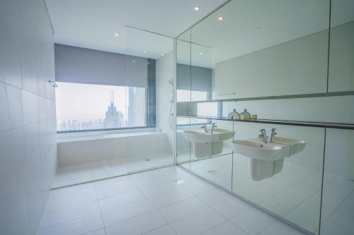 a white bathroom with two sinks and a window at Nasma Luxury Stays - Exquisite Hideaway With Awe-ins Burj Khalifa Views in Dubai