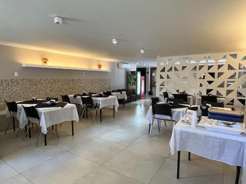 un comedor con mesas y sillas blancas y una pared en Riviera Hotel, en Brasilia