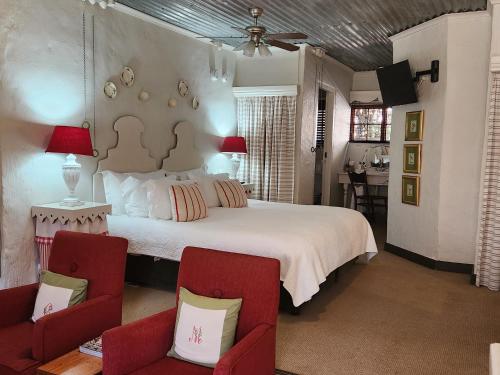 a bedroom with a large white bed and two chairs at Cleopatra Mountain Farmhouse in Fort Nottingham