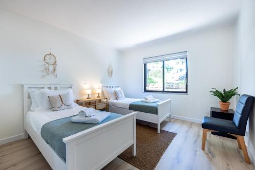 a bedroom with two beds and a chair at Muito Sol in Albufeira