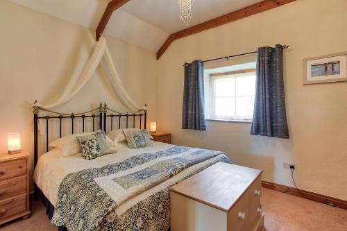 a bedroom with a large bed and a window at Rose Cottage, Tregolls Farm in Saint Wenn