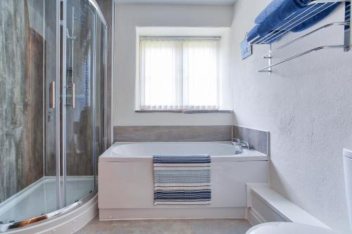a white bathroom with a tub and a shower at Rose Cottage, Tregolls Farm in Saint Wenn