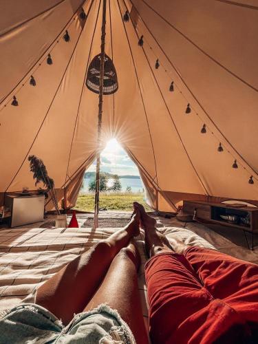 a person laying on a bed in a tent at Amberhouse Glempings in Piejūti
