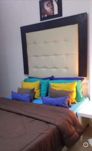 a bed with colorful pillows on it in a room at Agora in front of Marassi in Sīdī ‘Abd ar Raḩmān