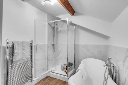 a white bathroom with a shower and a sink at The Woodrow Cottage in Cawston