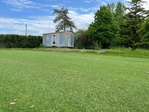 a small blue building in a field of grass at Cornwallis shepherds hut in Wix