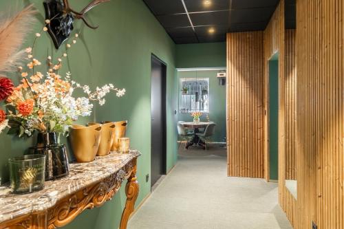 un pasillo con paredes verdes y un mostrador con jarrones. en Villa Alba, en Bilzen