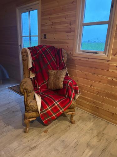 a blanket on a chair in a room with a window at Cornwallis shepherds hut in Wix