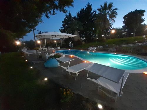 een zwembad met stoelen en 's nachts een parasol bij Luxury bnb Le Rocce in Villasmundo