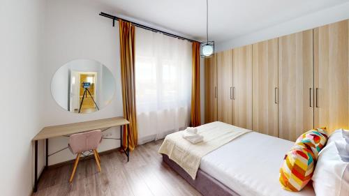 een slaapkamer met een bed, een bureau en een spiegel bij Deventer Residence VRT in Sibiu