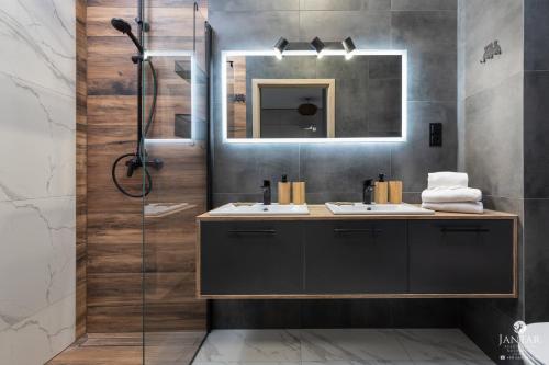 ein Bad mit einem Waschbecken und einer Dusche mit einem Spiegel in der Unterkunft Jantar Apartamenty - Baltic Marina Residence in Kołobrzeg