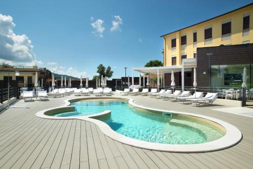 a swimming pool on a patio with chairs and a building at Hotel Ristorante Dante in Torgiano