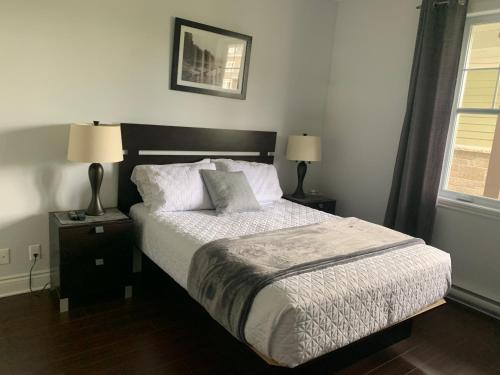 a bedroom with a bed with two lamps and a window at Condo Le Champlain-102 in Bromont