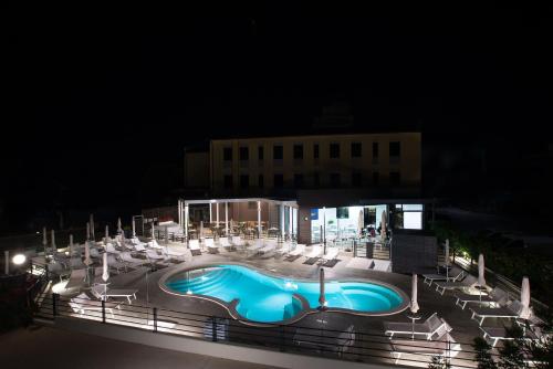 a swimming pool at night with chairs and a building at Hotel Ristorante Dante in Torgiano