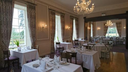 リークスリップにあるLeixlip Manor Hotelの白いテーブルと椅子、シャンデリアのあるレストラン