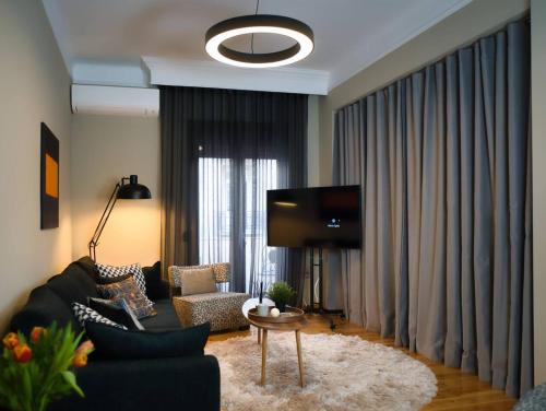 a living room with a black couch and a tv at 4 TRAVELERS Together in Thessaloniki