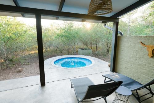eine Terrasse mit einem Pool, einem Tisch und Stühlen in der Unterkunft Veld Villa in Marloth Park