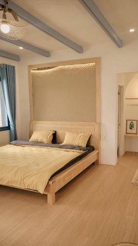 a bedroom with a large bed with a wooden headboard at Tomato Villa & Restaurant in Da Lat