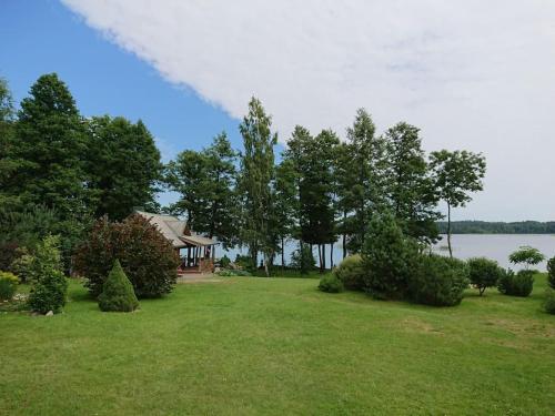 a house on a lawn with trees and a lake at Country side/Kaštonų alėja - Sodyba in Sudeikiai