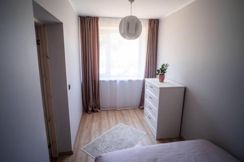 a bedroom with a bed and a dresser and a window at Cozy apartment in the city center of Kärdla in Kärdla