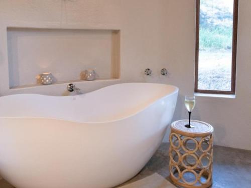 a white bath tub in a bathroom with a glass of wine at Nyala Safari Lodge in Hoedspruit