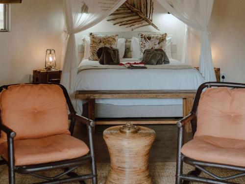 a bedroom with a bed and two chairs at Nyala Safari Lodge in Hoedspruit