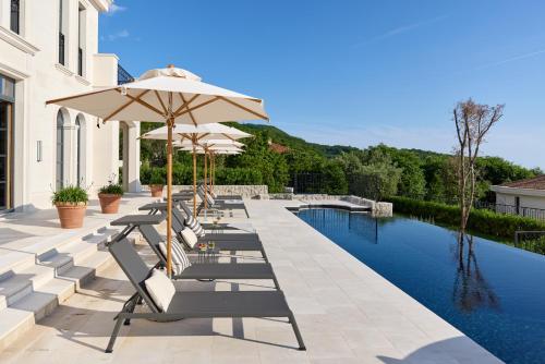 a row of chairs and umbrellas next to a pool at Eterno Villas in Budva