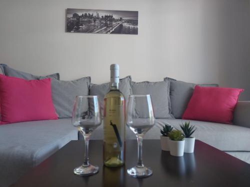 a bottle of wine and two wine glasses on a table at 1st Floor 1st Class Pool View Apt. in Paphos
