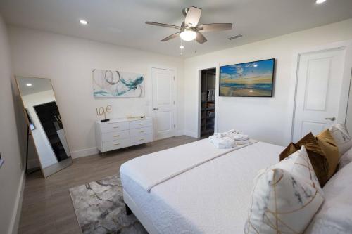 een witte slaapkamer met een bed en een plafondventilator bij Fantasy Resort OMG PoolWaterfall outdoorKitchn Gym in Lake Worth
