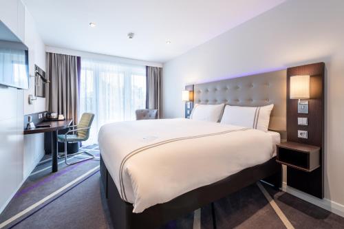 a hotel room with a large bed and a desk at Premier Inn München City Schwabing in Munich
