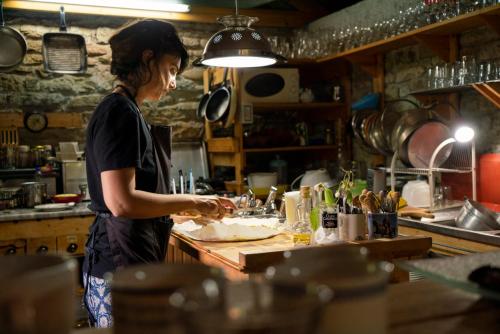 a woman standing in a kitchen preparing food at Ferma Albanik in Këlcyrë