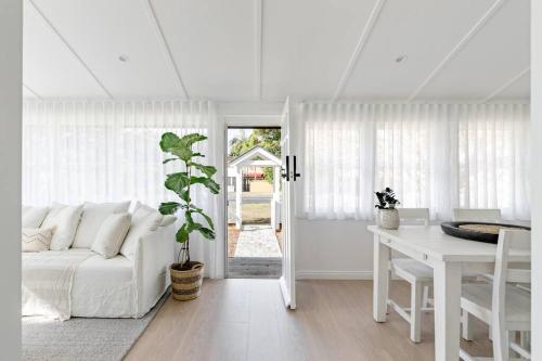 a white living room with a white couch and a table at Steamers Bungalow in Huskisson