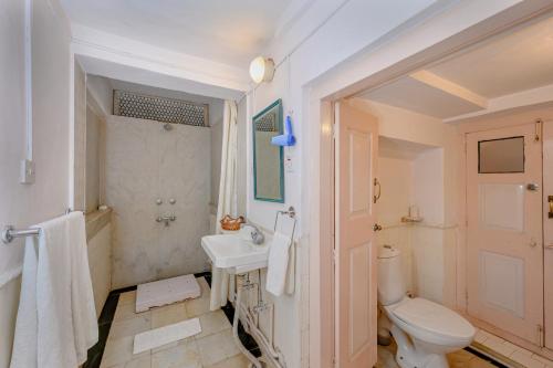 Baño blanco con aseo y lavamanos en Neemrana's - Piramal Haveli, en Bagar