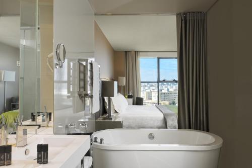 a bathroom with a large tub and a bed at Melia Braga Hotel & Spa in Braga