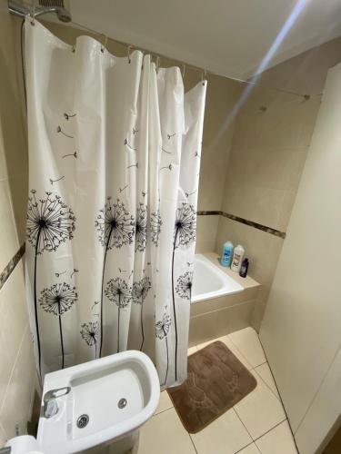 La salle de bains est pourvue d'un rideau de douche avec des danses. dans l'établissement Departamento en Caballito con Sauna y Pileta,en Caballito, à Buenos Aires