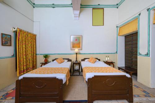 a room with two beds in a room at Neemrana's - Piramal Haveli in Bagar
