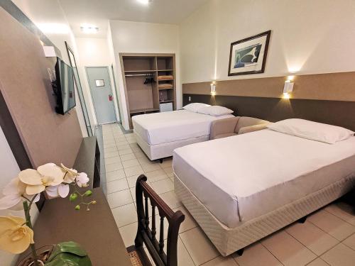 a hotel room with two beds and a table at Athus Brasilia Hotel - Antigo Aristus in Brasilia