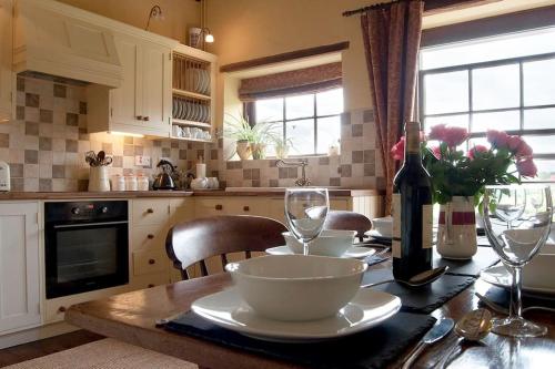 a kitchen with a table with a bowl and wine glasses at Bach y Graig cottage in St Asaph