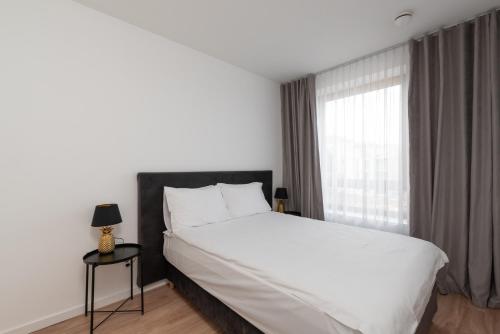 ein Schlafzimmer mit einem großen weißen Bett und einem Fenster in der Unterkunft Brand New and Modern 1BDR Apartment in Vilnius