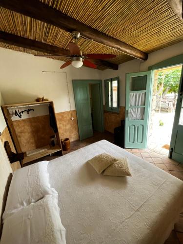 1 dormitorio con cama blanca y ventilador de techo en Graziosa stanza campidanese Su segundu, en Oristano