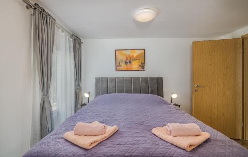 a bedroom with a purple bed with two towels on it at Apartmani M in Baška